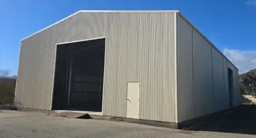 NBT Construction shed builder homepage image of a very large commercial shed with large roller door and small door access.